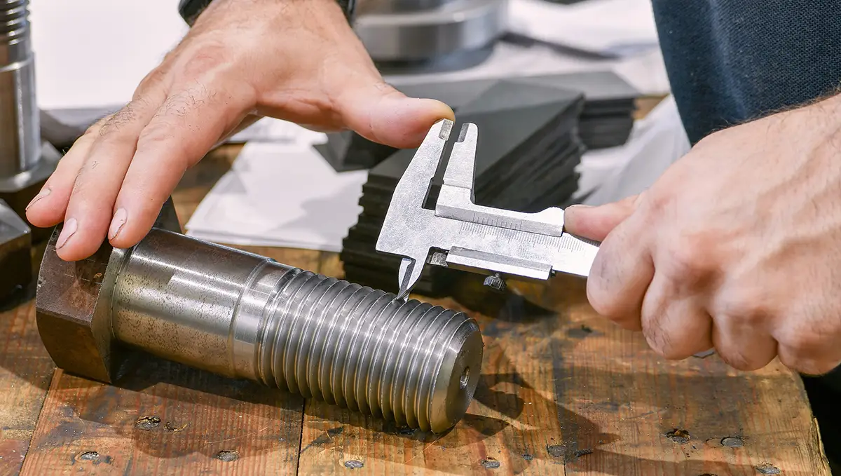 worker measures the thread pitch with a vernier caliper