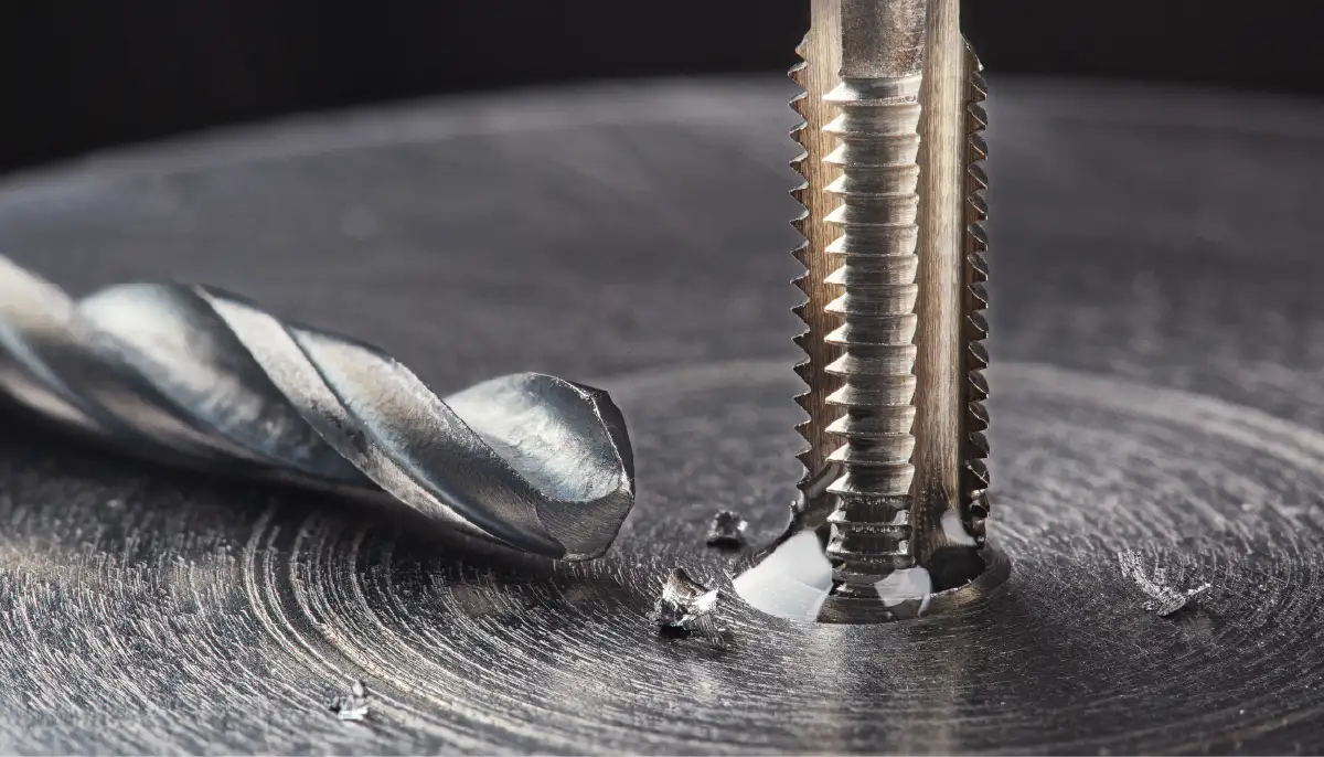 Gewindeschneider schneidet ein Innengewinde in ein Metallloch neben einem Spiralbohrer