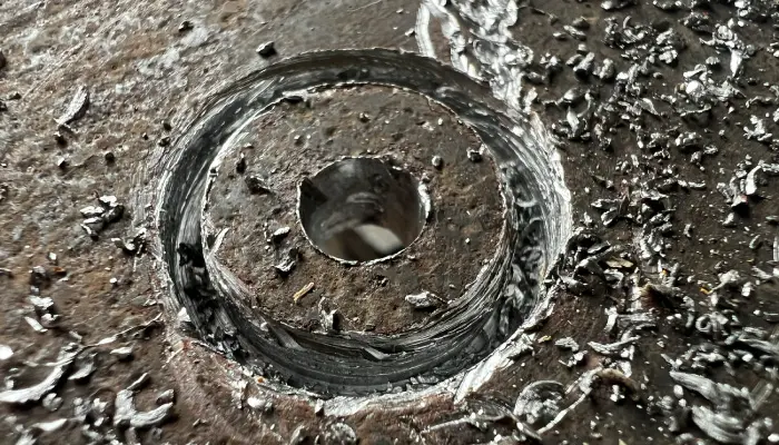 Mit Lochbohrer Metall gesägtes rundes Loch in Metallplatte mit Metallspänen – Lochsäge Ergebnis