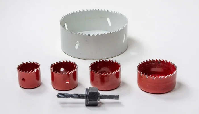 Lochsäge Metall Set: Verschiedene Größen roter Lochbohrer mit Zentrierbohrer und Adapter auf weißem Hintergrund