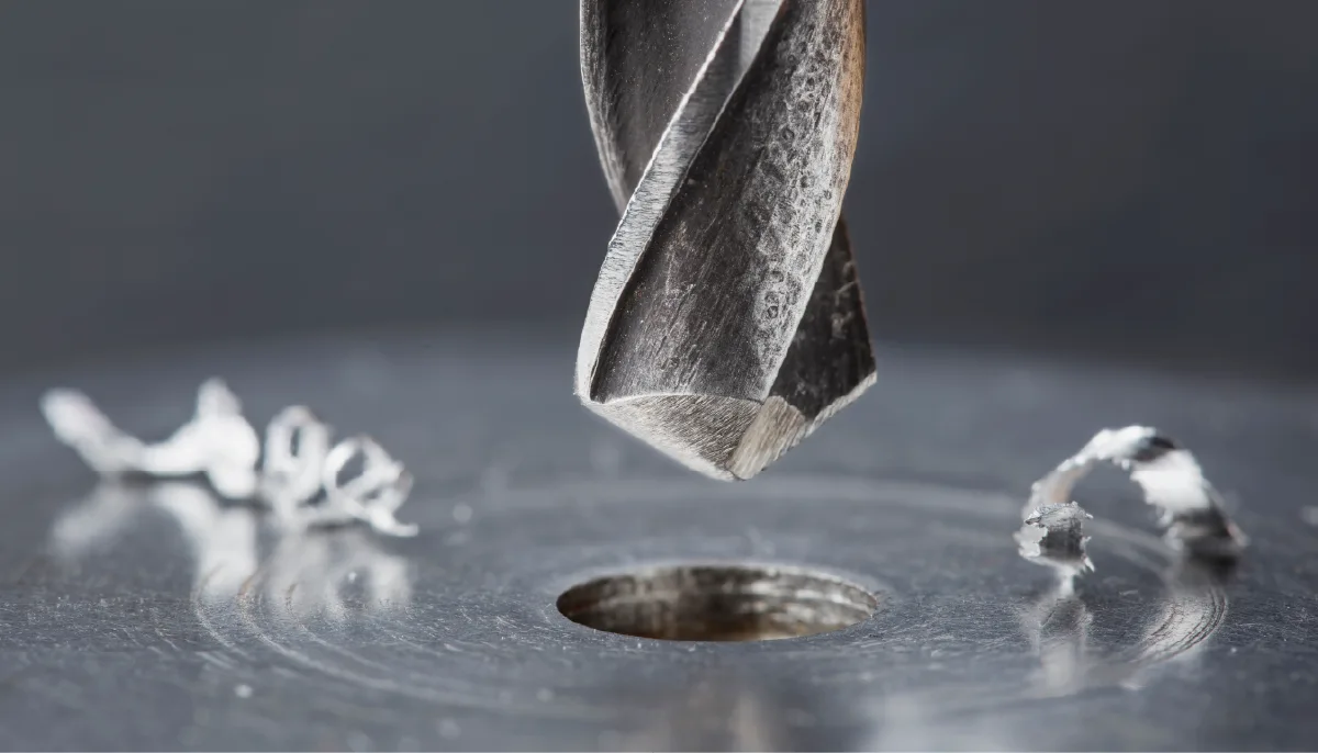 Metallbohrer über gebohrtem Loch in Metall