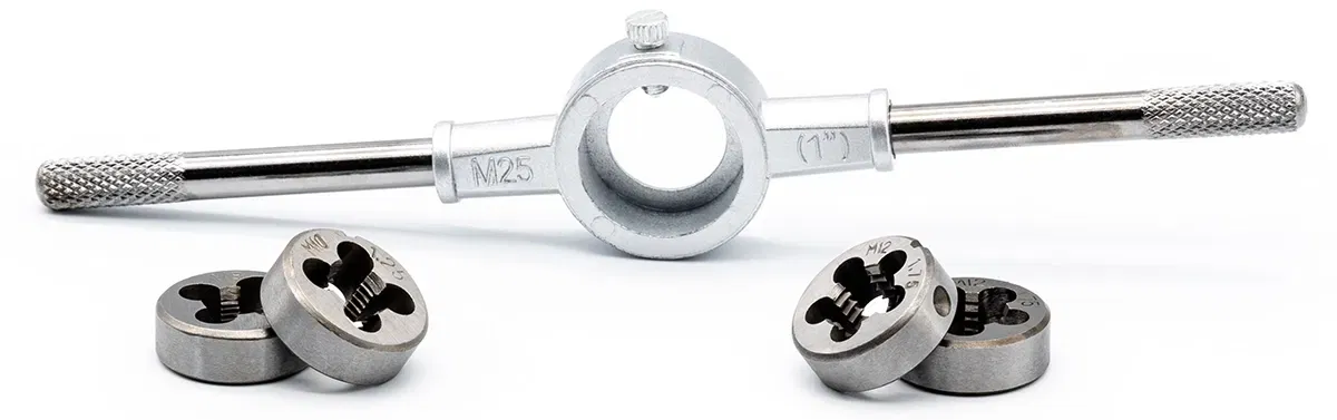 Four round dies of different sizes lie in front of a die holder Four round dies of different sizes lie in front of a die holder